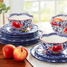 a table topped with blue and white plates covered in fruit next to a vase filled with peaches