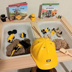 two bins filled with construction toys and books on top of a wooden table in front of a white wall