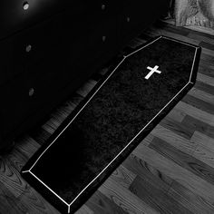 a black and white photo of a cross laying on the floor next to a bed