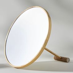 a mirror that is on the ground with a wooden stick sticking out of it's side