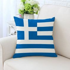 a blue and white pillow sitting on top of a couch next to a vase with flowers