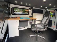 the interior of a camper van with an office chair and desk in front of it