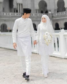 a man and woman dressed in white holding hands