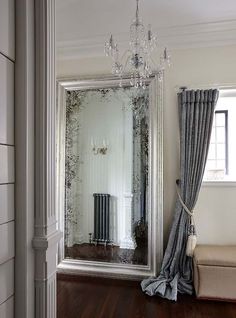 a large mirror sitting on top of a wooden floor next to a couch and window