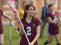 a girl holding a lacrosse stick and wearing a number two jersey with the number 2 on it