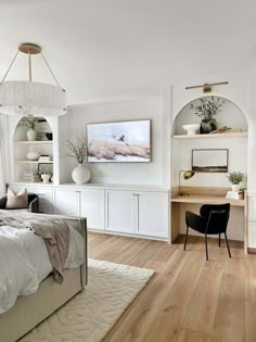 a bedroom with white walls and wood flooring has a bed, desk, chair, bookshelf and artwork on the wall