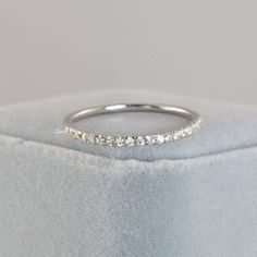 a white gold wedding band with five diamonds on it's side, sitting in a velvet box