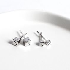 Add a playful touch to your look with our Sterling Silver Dice Stud Earring. The dice shape is perfect for anyone who loves games or gambling, and the rhodium plating adds a sleek, polished finish. The earring is made of high-quality sterling silver, ensuring that it will last for years to come. These earrings are perfect for everyday wear or for a special occasion. They make a unique gift idea for anyone who loves quirky, one-of-a-kind accessories. The earring is secured with a post and back, ensuring a comfortable fit. Material:  S925 sterling silver Silver is a hypoallergenic metal, it brings you more comfort but less irritation. Surface plated rhodium to prevent oxidize and tranish. Size: Length: 3 mm ( Large ) / 2 mm ( Small ) Precious metal mass: approx. 0.85 (Large) / 0.3 (Small) gr Silver Cube Earrings For Gifts, Dice Earrings, Cube Earrings, Ear Stud, Belly Rings, Sterling Silver Studs, Sterling Silver Earrings Studs, Ear Studs, Stud Earring