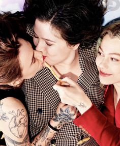 two women are kissing and one is holding a toothbrush while the other looks at her