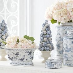 three blue and white vases with flowers in them sitting on a mantle next to other decorative items