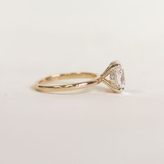 a yellow gold engagement ring with a pear shaped diamond in the center, on a white background