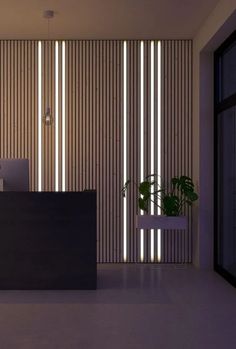 a reception desk in front of a wall with vertical blinds and a potted plant