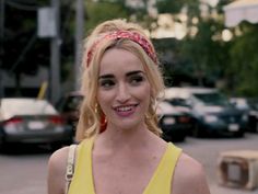 a woman in a yellow top smiles at the camera while wearing a red headband