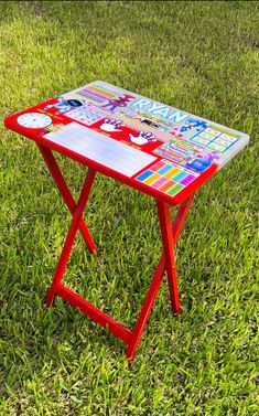 a red table sitting on top of a lush green field