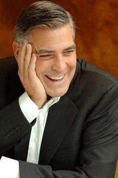 a man sitting at a table with his hand on his head and smiling for the camera