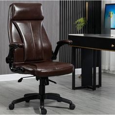 a brown leather office chair sitting in front of a computer desk