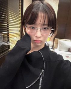 a young woman wearing glasses is taking a selfie in front of a mirror with her hand on her head