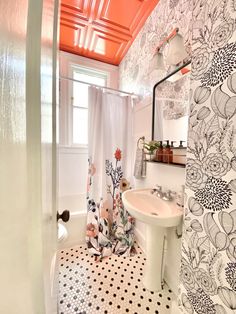 a bathroom with black and white tile flooring and orange painted ceiling above the sink