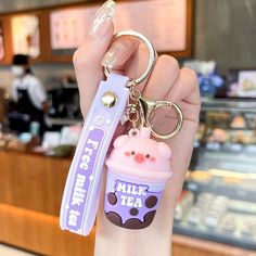 a hand holding a keychain with an ice cream cup on it that says milk tea