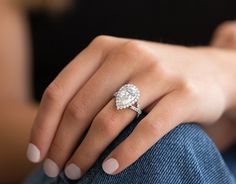 a woman's hand with a diamond ring on her left hand, sitting down