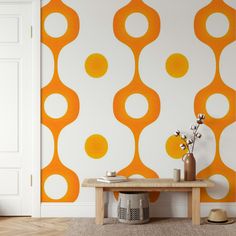 an orange and white wallpaper in a living room with a table, vases and chair