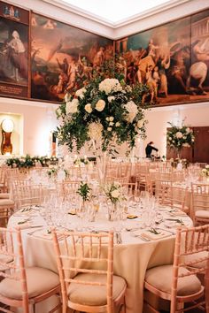 the tables are set with white flowers and champagne glasses in front of paintings on the wall