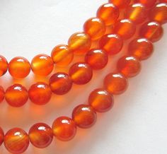 three strands of orange glass beads on a white surface