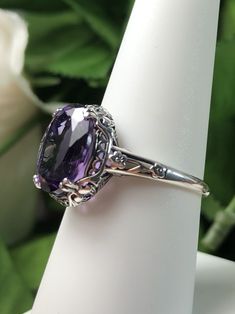 "Natural Purple Amethyst Ring Description Edward Design#70 (smaller version) MADE TO ORDER Inspired by Edwardian jewelry of the early 1900s, I now offer this lovely Antique reproduction ring in sterling silver. This gorgeous ring is set with a stunning 3.32ct Natural purple amethyst gemstone. This genuine amethyst has excellent color and clarity. The oval cut amethyst is 12mm (1/2th of an inch) Long by 10mm Wide (3/8th\"). The ring sits 6mm off the finger. The inside of the band s marked 925 for Elegant Oval Solitaire Gemstone, Classic Oval Purple Gemstones, Classic Oval Amethyst Ring With Accent Stones, Oval Amethyst Ring With Intricate Design, Classic Purple Oval Gemstones, Purple Oval Classic Gemstones, Formal Amethyst Cushion Cut Ring With Accent Stones, Vintage Oval Gemstones For Wedding, Oval Vintage Gemstones For Wedding