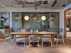 a dining room table and chairs with plants on the wall behind it in an office setting