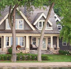 a large house with lots of windows and trees in front of the water's edge