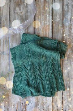 a green knitted sweater sitting on top of a wooden floor