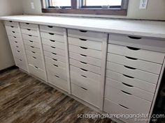 a white dresser with drawers and a large mirror on the wall above it, in front of a window