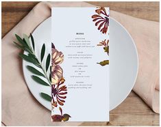 the menu card is on top of a plate with leaves and flowers in front of it