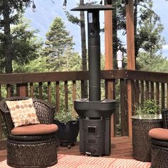 a wood stove sitting on top of a wooden deck next to two wicker chairs