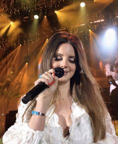 a woman with long hair holding a microphone in front of her face and singing on stage