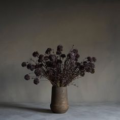 a vase filled with purple flowers sitting on top of a white tablecloth covered floor