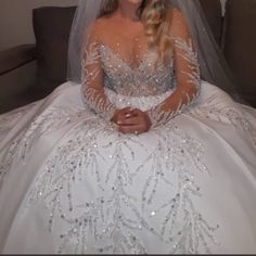 a woman in a white wedding dress sitting on a couch wearing a veil and tiara