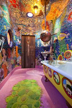 this bathroom has colorful walls and floors with lots of artwork on the walls, along with a large bathtub