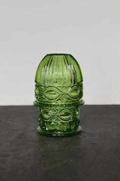 a green glass vase sitting on top of a table