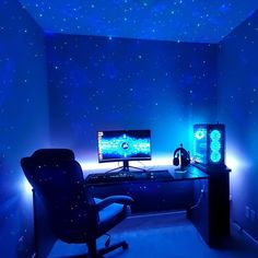 a computer desk with two monitors and headphones on it in a room lit by blue lights