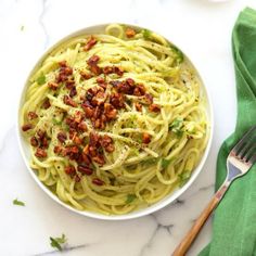 a white bowl filled with pasta and topped with bacon