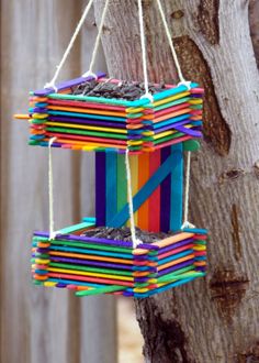 a colorful bird feeder hanging from a tree with strings attached to it's sides