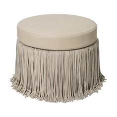 a white ottoman with fringes on it and a round cushion in the middle,