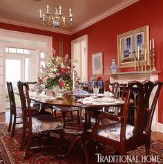 a formal dining room with red walls and chandelier