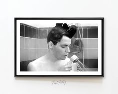 a black and white photo of a shirtless man brushing his hair in the shower