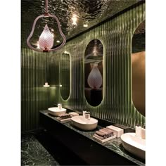 a bathroom with green walls and two sinks in front of the mirror that is hanging from the ceiling