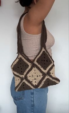 a woman is holding a crocheted bag in front of her back and the bottom half of her body