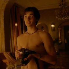 a shirtless man holding a camera in his hand