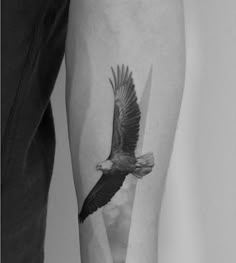 a black and white photo of an eagle tattoo on the right arm, with wings spread out