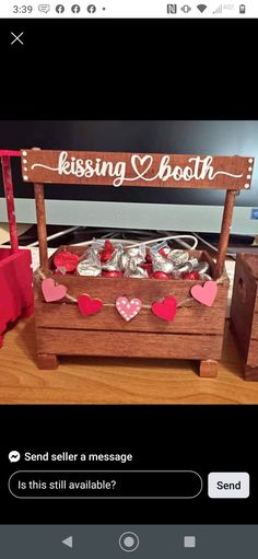 a wooden box filled with lots of hearts next to a sign that says kissing booth